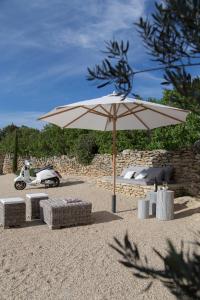 a tan umbrella and chairs and a table and a scooter at Villa Vagabonde in Gordes +42 photos