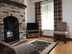 a living room with a brick fireplace and a television at Craigs Rock Cottage Cookstown in Cookstown