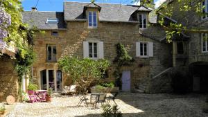 une ancienne maison en pierre avec une table et des chaises dans l'établissement Le Clos du Barry, à Sévérac-lʼÉglise