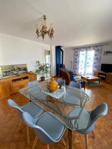 ein Wohnzimmer mit einem Glastisch und Stühlen in der Unterkunft Villa Bel-horizon, soleil du sud in Bagnols-sur-Cèze