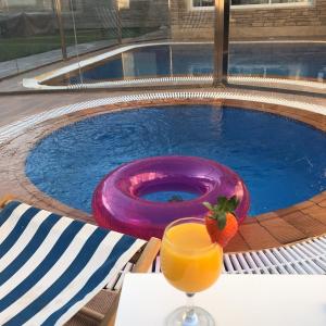 een glas sinaasappelsap en een frisbee naast een zwembad bij Diva Chalet in Riyad