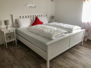 two white beds with red pillows in a bedroom at Surrbach Chalet in Baiersbronn