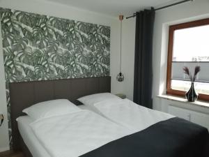 uma cama num quarto com um papel de parede frondoso em Apartment Enjoy em Büsum