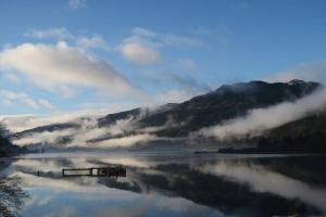 a body of water with a reflection of a mountain at TwoStones Self Catering Cottage in Arrochar +6 photos