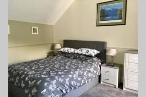 a bedroom with a bed with a black and white comforter at TwoStones Self Catering Cottage in Arrochar