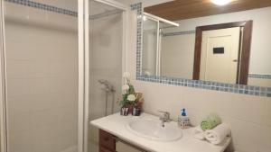 een badkamer met een wastafel en een douche met een spiegel bij Casa Dos Nenos in Pacios