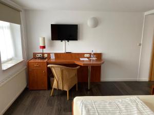 Habitación con escritorio, TV y cama. en Weserlounge Apartments, en Hessisch Oldendorf