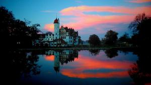 a castle sitting on top of a lake at sunset at „Rentmeisterhaus Basedow“ in Basedow