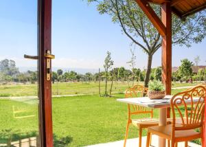 uma mesa e cadeiras num alpendre com vista para um campo em The Village- Jordan Riverside Travel Hotel em Sede Neẖemya