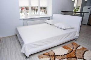 un letto bianco con 2 cuscini e un tappeto di Студія, вул. Сумгаїтська, 24, центр ПЗР a Čerkasy