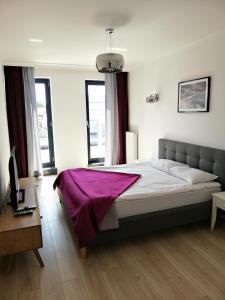 sypialnia z łóżkiem z fioletowym kocem w obiekcie Apartamenty Kropla Bałtyku w mieście Darłowo