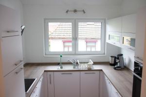 uma cozinha branca com um lavatório e uma janela em Köpfchen-Ferienwohnungen – Wohnung Köpfle em Untermünstertal