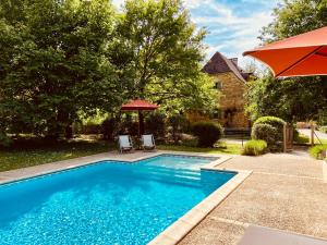a swimming pool with two chairs and an umbrella at La Closerie de Sarlat Maison d hôtes de charme in Sainte-Nathalène