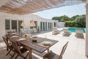 un patio con mesa, sillas y piscina en Villa Linda en Aldeia do Meco
