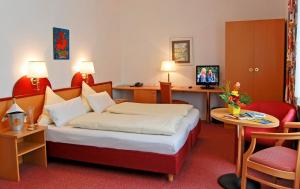 メンディヒにあるHANSA Hotelのベッドとデスクが備わるホテルルームです。