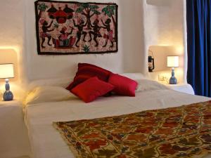 a bedroom with a bed with two red pillows at Casa Simonetta in Carloforte