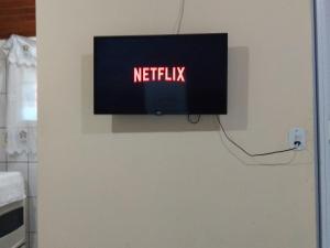 uma televisão numa parede com o sinal de netflix em Chalé suíte com ar em Resende em Resende