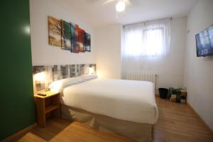 Un dormitorio con una gran cama blanca y una ventana en Aralso Santa Isabel, en Segovia