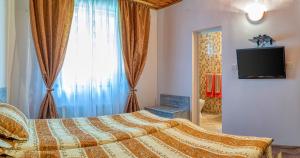 a bedroom with a bed and a tv and a window at Крушун - Единствена на метри от водопадите, Krushun - The only stay just meters from the waterfalls in Krushuna