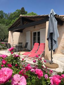 a patio with chairs and an umbrella and pink flowers at Villa du Sud in Vence