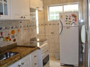 uma cozinha com um frigorífico branco e um lavatório em APARTAMENTO EM SÃO VICENTE - SP em São Vicente