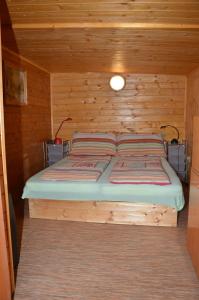 łóżko w domku z drewnianą ścianą w obiekcie Penzion Slunce nad Vinným Sklepem w mieście Moravská Nová Ves
