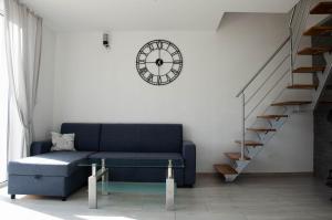 a living room with a blue couch and a clock at Domki na Wzgórzu - Rospuda in Filipów
