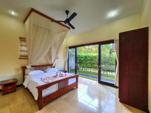 a bedroom with a bed and a large window at Sayang Taman Villas in Sanur