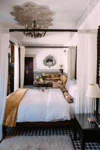 a bedroom with a large white bed with a chandelier at Riad Maison Bleue and Spa in Fès