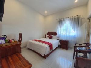 Schlafzimmer mit einem Bett, einem Tisch und einem Fenster in der Unterkunft Royal Hotel in Bạc Liêu