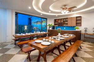 uma sala de jantar com mesas de madeira e uma grande janela em Seaweed Luxury Villa & Spa em Hoi An