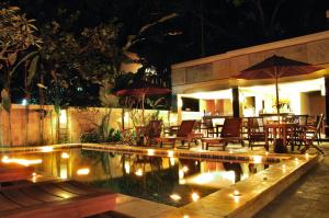 a swimming pool with chairs and a restaurant at night at Sari Villa Sanur Beach in Sanur