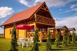 una cabaña de madera con una mesa y sillas frente a ella en Mazurska Przystań, en Giżycko
