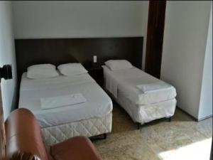 a bedroom with two beds and a chair in it at OYO Hotel Ana Cassia in Manaus