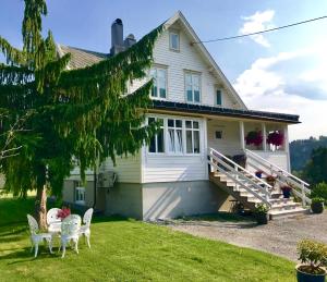 a white house with chairs and a porch at Villa Lovise Riverside in Stranda