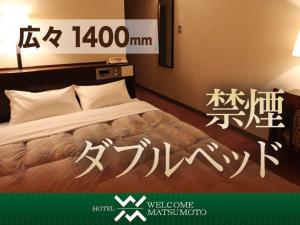 a hotel room with a bed with writing on it at Hotel Welcome Matsumoto in Matsumoto