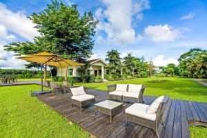 a wooden deck with chairs and an umbrella at Ville Greensward in Taitung City