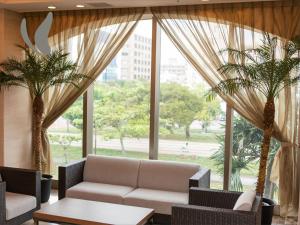 a living room with a couch and two palm trees at Almont Hotel Naha Omoromachi in Naha