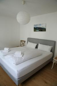 Cama blanca con sábanas y almohadas blancas en Apartment Seeglück am Schliersee - modern, zentral, perfekt für Familien, en Schliersee