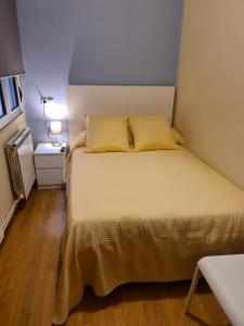 uma cama com almofadas amarelas num pequeno quarto em El Vasco Rooms em Oviedo