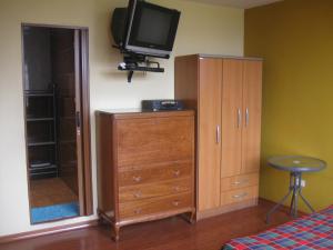 a bedroom with a dresser and a tv on the wall at Posada Peregrinus in Lima