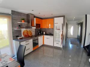 una cocina con electrodomésticos blancos y armarios naranjas en Wellenreiter 1, en Breege 4 fotos más