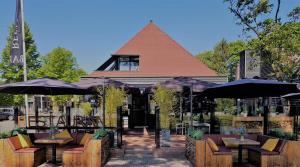 a restaurant with tables and umbrellas in front of a building at Hotel Bieze in Borger