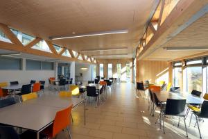 uma sala de jantar com mesas, cadeiras e janelas em Hôtel Centre Saint-François em Delémont