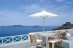 a white table and chairs and an umbrella on a balcony at Manos Small World in Firostefani