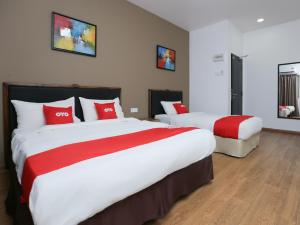 two beds in a hotel room with red pillows at OYO 89915 East Mount Hotel in Kukup