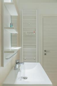 a white bathroom with a sink and a mirror at ATLAS UNIRII: Upscale Flats in the Heart of Bucharest! in Bucharest