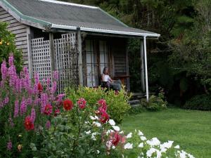 a woman sitting on a bench in a house with flowers at The Innlet, Country Apartments and Cottages in Collingwood