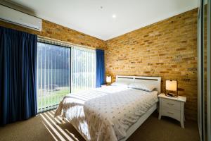 une chambre avec un lit et un mur de briques dans l'établissement Beachfront Escape, à Forster 14 autres photos