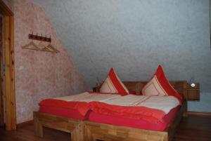 1 dormitorio con 1 cama con almohadas rojas y blancas en FH Am Osterbrunnen, en Hinterhermsdorf